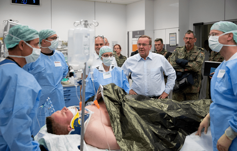 Boris Pistorius lässt sich in einem Krankenzimmer von Ärztinnen und Ärzten die Behandlung eines Probe-Patienten erläutern.