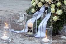 Neben einem Trauerkranz brennt eine Kerze, an der ein Foto von Hans und Sophie Scholl angebracht ist.