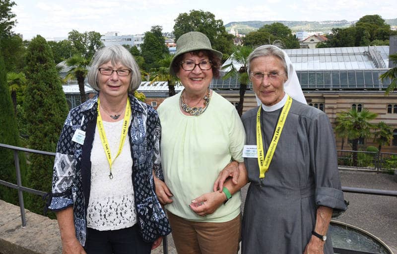 Gerlinde Kretschmann steht mit zwei Frauen in der Wilhelma, im Hintergrund erhebt sich das Stadtpanorama von Stuttgart.