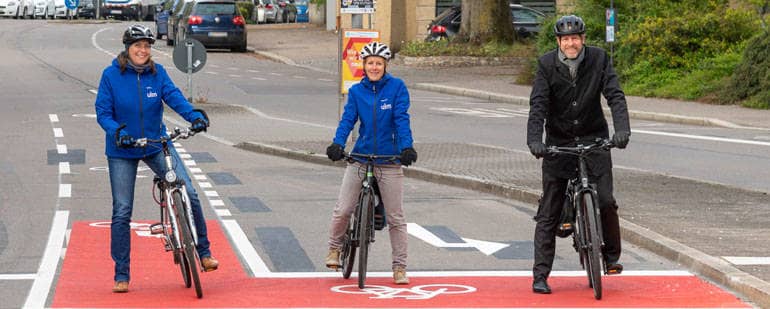 Zwei Frauen und ein Mann stehen auf Fahrrädern auf einer Straße
