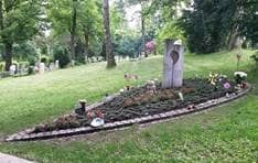 Grabanlage, auf der neben Blumen auch kleine Windspiele aufgestellt sind