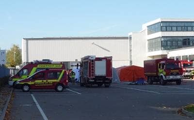 Ein Teil der Katastrophenschutzfahrzeuge der Feuerwehr Ulm stehen bei einer Übung auf einem großen Parkplatz. Dahinter sind die Zelte zur Dekontamination von Verletzten erkennbar.