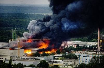 Bild eines Großbrandes einer Recyclingfirma aus großer Entfernung aufgenommen. 5000 Quadratmeter Halle stehen im Vollbrand. Flammenhöhe über 30 Meter und eine 100 m hohe schwarze Rauchsäule steht über dem Objekt.