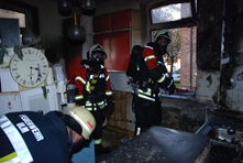Ein Angriffstrupp der Feuerwehr Ulm führt unter Atemschutz in einer ausgebrannten Küche Nachlöschareiten durch. Er demontiert dabei die Küchenmöbel.