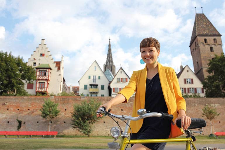 Frau mit Fahrrad vor der Ulmer Stadtmauer