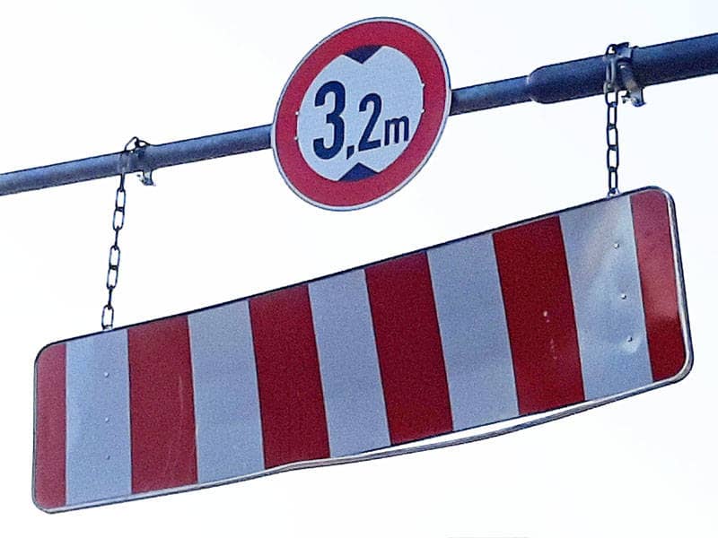 Ein beschädigtes Schild, das eine Höhenbeschränkung von 3,2 Metern anzeigt.