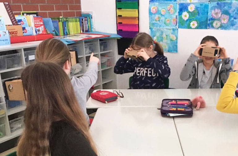 Junge Schülerinnen lesen durch ein Gerät im eingebauter 3D-Brille.