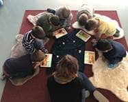 Kinder sitzen in einem Kreis herum und betrachten eine Darstellung auf ihren Tablets.