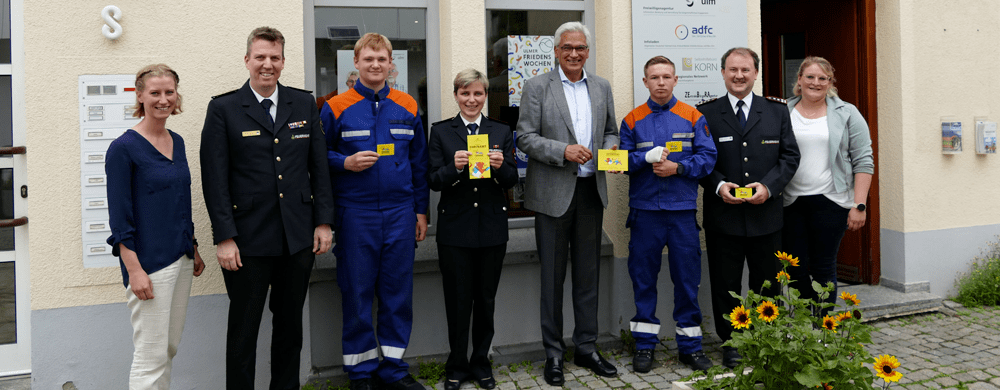 Acht Personen mit Ehrenamtskarten in den Händen vor dem Gebäude des Vereins "engagiert in Ulm" in der Radgasse