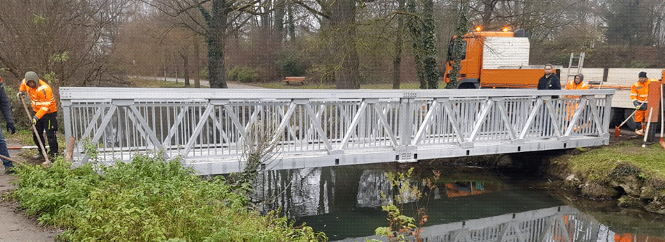 Eine kleine Brücke aus Aluminium, die über einen kleinen Bach führt