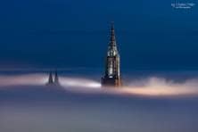 Der Hauptturm des Münster und die beiden Chortürme ragen aus dem Nebel in den Himmel empor.
