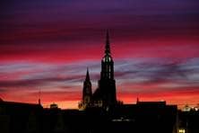 Das Ulmer Münster erhebt sich als Schatten vor dem Abendrot.