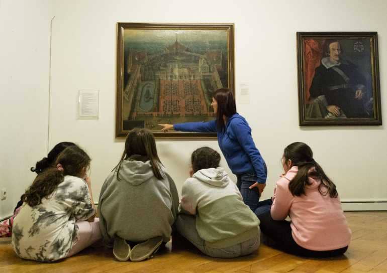 Eine Gruppe von Kindern sitzt vor einem Bild in einem Museum