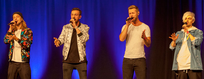 Vier junge Männer singen vor Publikum.