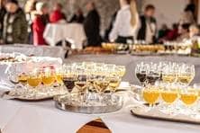 Gläser mit Wein, Orangensaft und Wasser stehen auf einem langen Tisch.