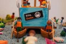 Playmobilfiguren mit Paddel in der Hand auf kleinen, gebastelten Booten