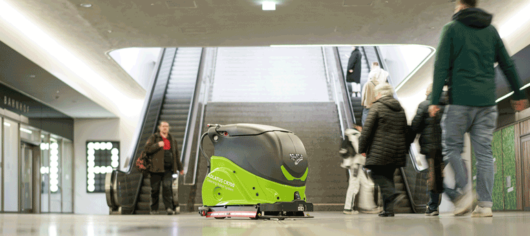 Ein grün-grauer Roboter bewegt sich in einer Gruppe von Menschen in der Sedelhofpassage
