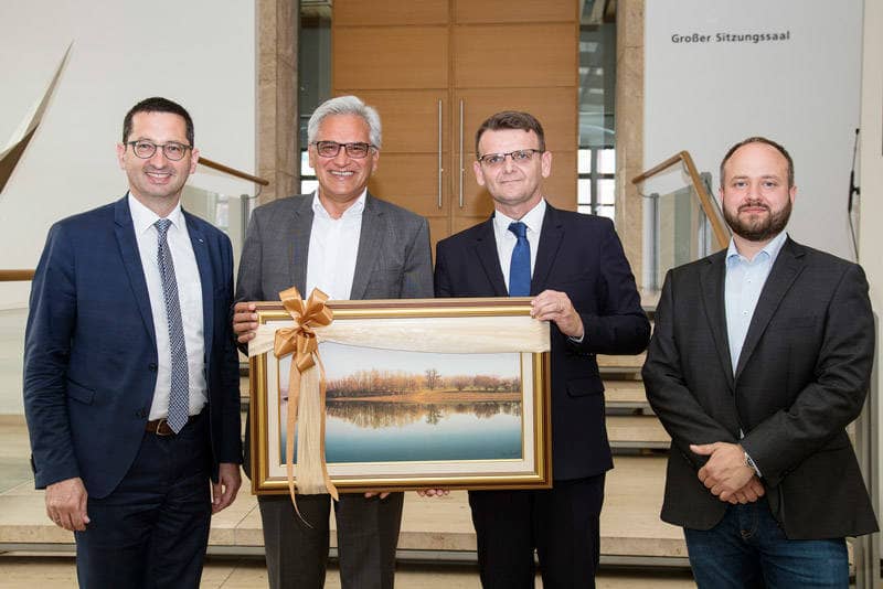 Ein Gemälde mit einem Fluss und Uferpflanzen wird an Oberbürgermeister Czisch übergeben.