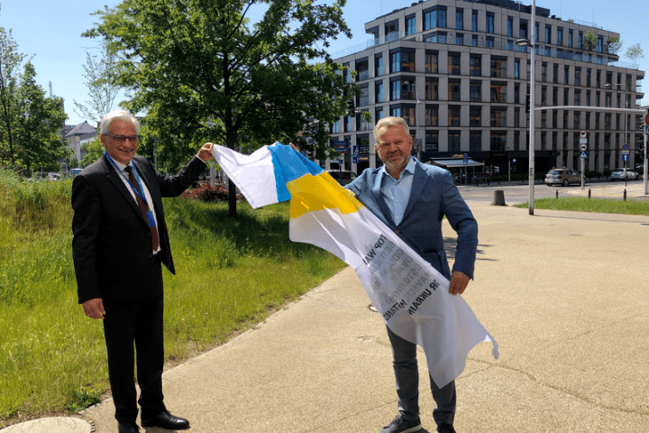 Gunter Czisch und Anatolli Fedoruk halten gemeinsam eine wehende Fahne.