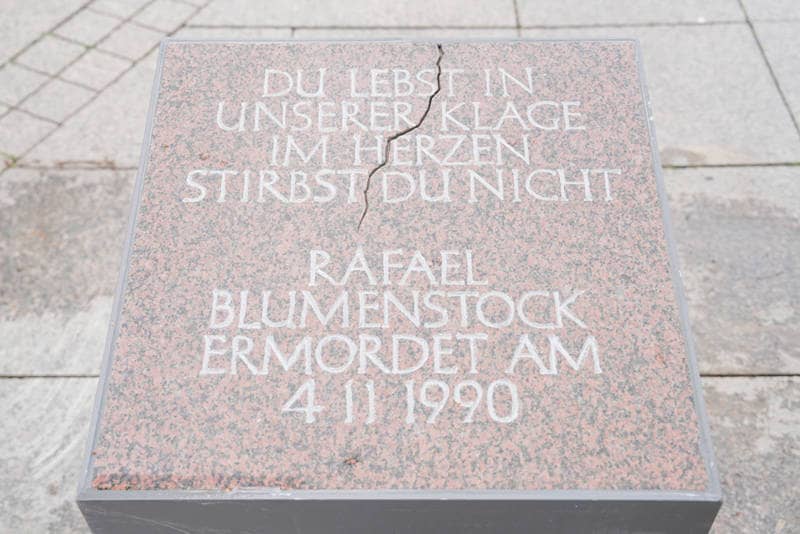Eine Granitplatte mit der Aufschrift: „Du lebst in unserer Klage – im Herzen stirbst du nicht – Rafael Blumenstock, ermordet am 4.11.1990“. 