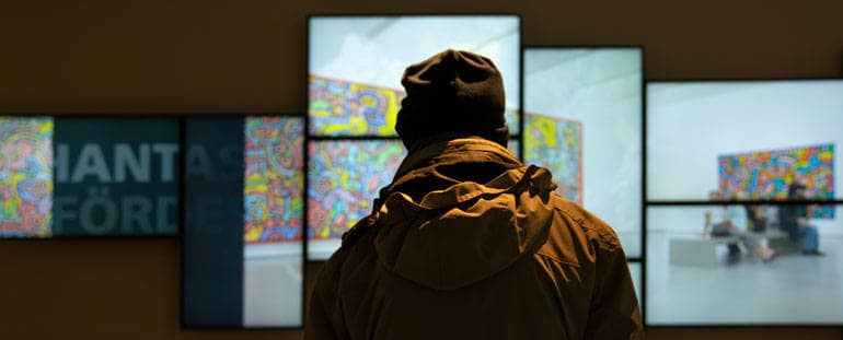 Ein Mann steht in einem dunklen Raum vor einer Monitorwand