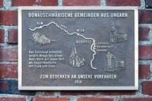 Eine Tafel, auf der zu lesen steht: "Das Schicksal schnitzte unsere Wiege aus Ulmer Holz, doch wir leben fern aus Ungarndeutsche mit Fleiß und Stolz."