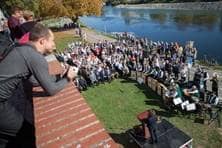 Dutzende Menschen beobachten das Zeremoniell am Donauufer.