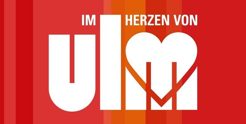 Logo mit rotem Hintergrund und der Aufschrift "Im Herzen von Ulm"