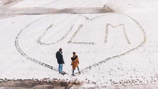 Zwei Leute haben in den Schnee den Umriss eines Herzens getreten