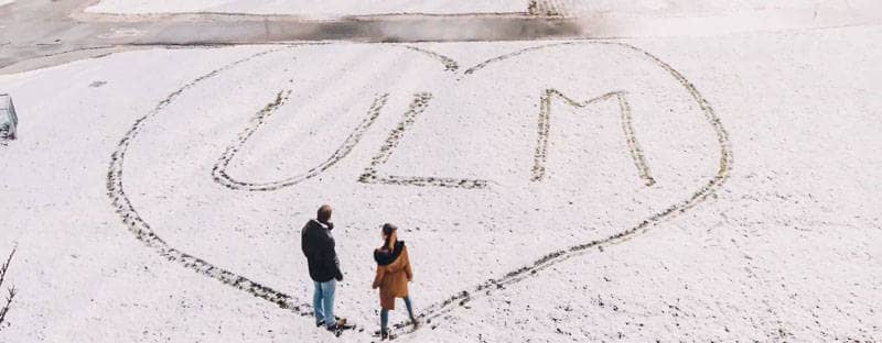 Zwei Leute haben in den Schnee den Umriss eines Herzens getreten