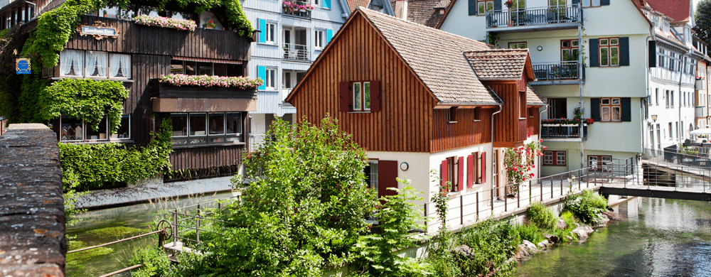 Alte Häuser stehen am Ufer eines kleinen Flusses.