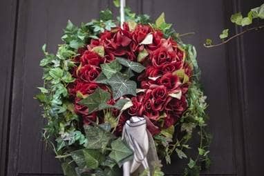 Ein Kranz aus Rosen und Efeu hängt an der Tür des Schönen Hauses.