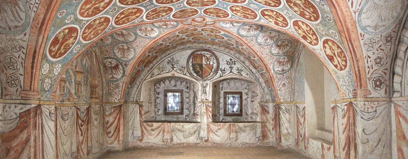 Kunstvolle Malereien zieren einen Saal mit alten Fresken.