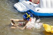 Ein Mann, der sich zahlreiche leere Plastikflaschen umgebunden hat, schwimmt im Wasser.