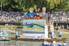 Auf einem Boot sind Figuren des Oberbürgermeisters und des Baubürgermeisters im Comic-Stil aufgestellt