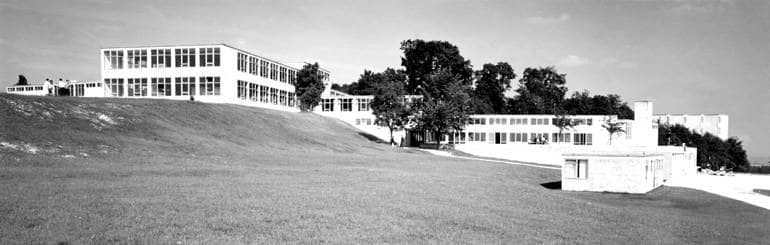 Schwarz-weiß-Aufnhame von einem weitläufigen Hügel, auf dem sich die Flachdach-Bauten der Hochschule für Gestaltung erheben.