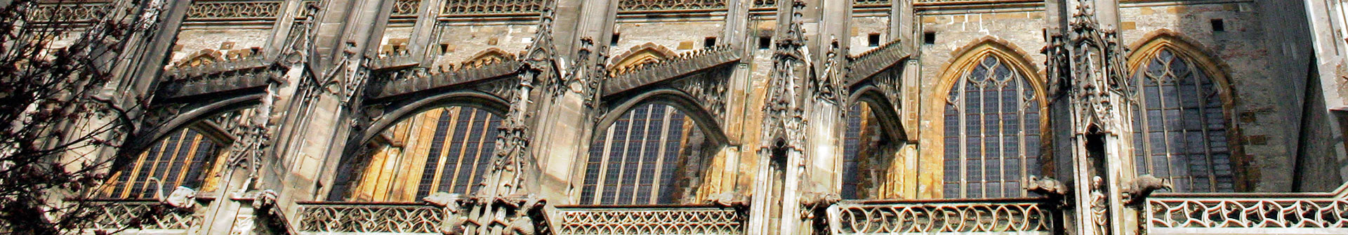 Außenwand des Ulmer Münsters mit hohen Fenstern und kunstvollen Türmchen