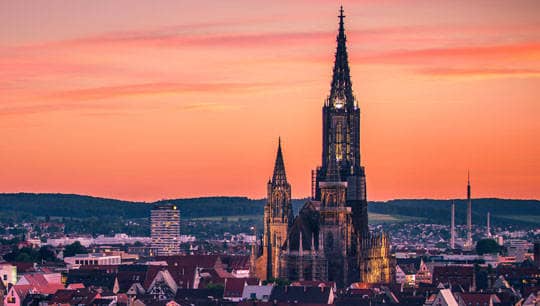 Das Ulmer Münster ragt bei Sonnenuntergang in den Himmel.
