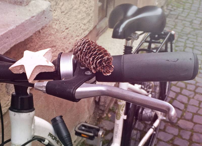 Ein Fichtenzapfen und ein Zimtstern liegen auf einem Fahrradlenker.