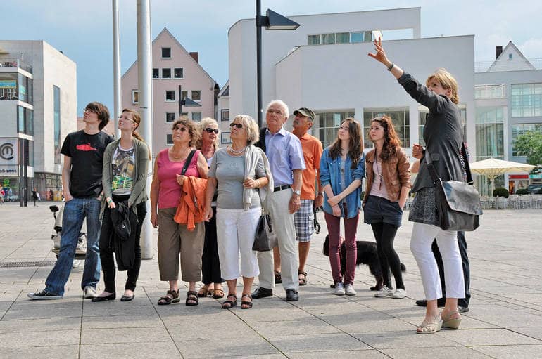 Eine Stadtführerin mit einer Gruppe von Touristen auf dem Münsterplatz