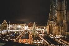 In der Dunkelheit erleuchten der Weihnachtsbaum und die Buden drumherum auf dem Münsterplatz.