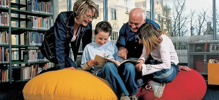 Eine Familie liest in der Kinderbibliothek zusammen ein Buch. 